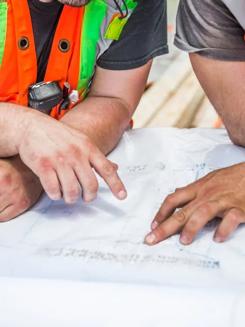 Site workers in high-visibility vests reviewing plans together