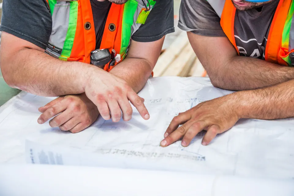 Site workers in high-visibility vests reviewing plans together