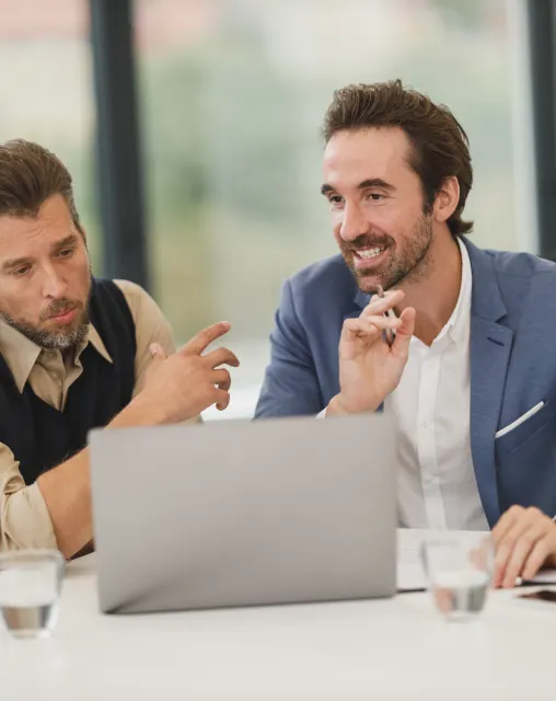 Two colleagues discussing work at a laptop in a bright office