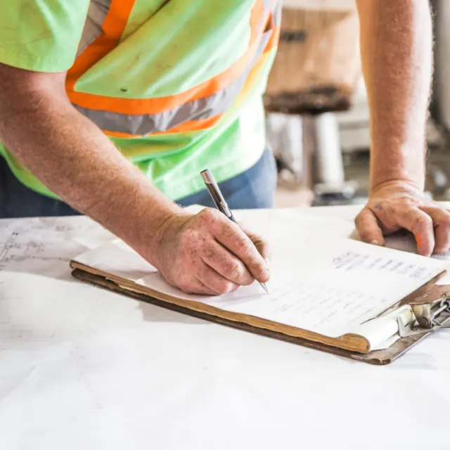 Worker completing a timesheet on a clipboard